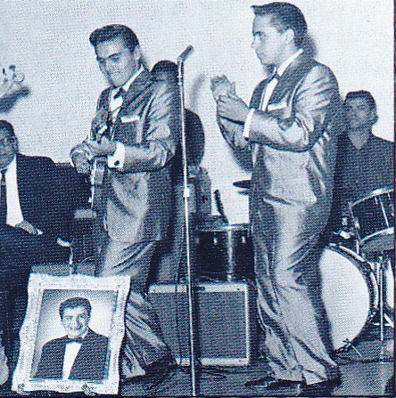 The Addrisi Brothers performing in matching suits as the opening act for Ritchie Valens, whose portrait is at the front of the stage